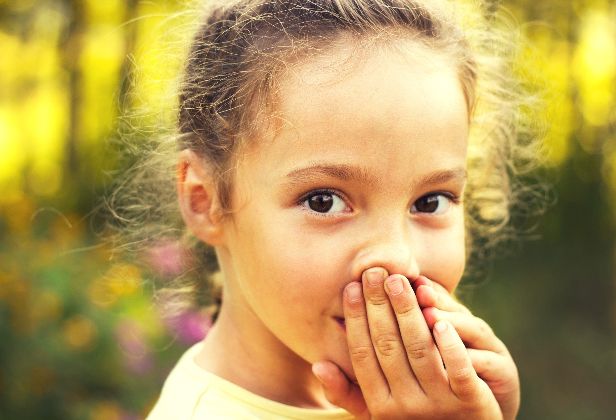 little girl covering her mouth with her hands
