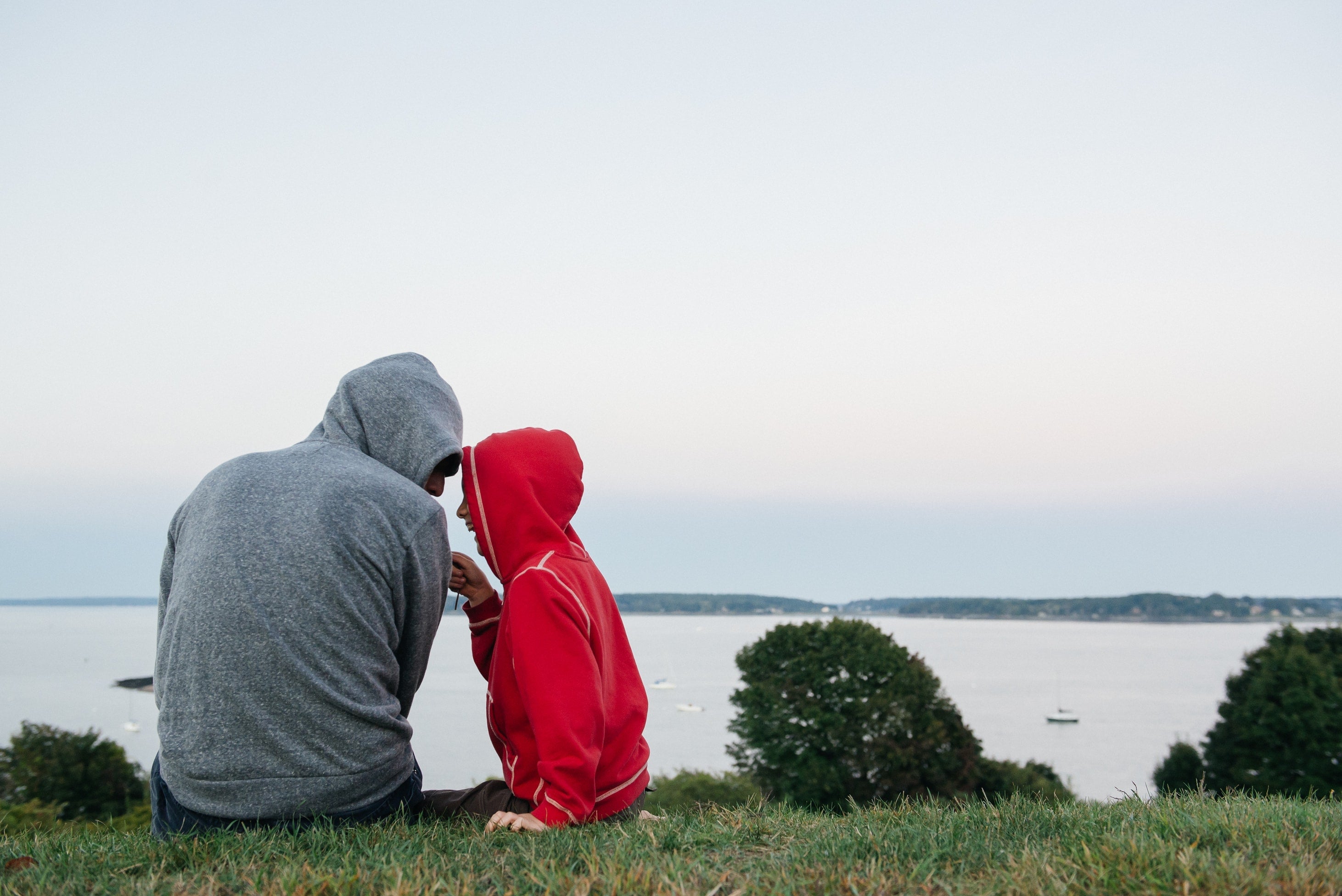 father and son on top of a hill together enjoying the view
