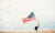 woman holding a flag in a wheat field