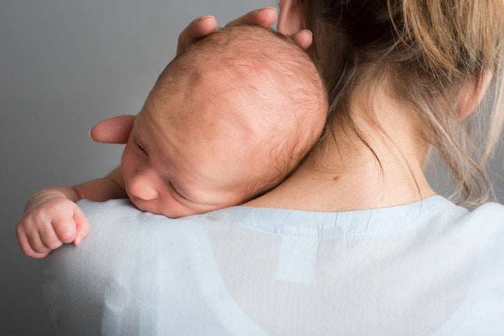 A baby is sleeping on its mothers shoulder