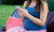 A pregnant lady using phone sitting on a bench outside.