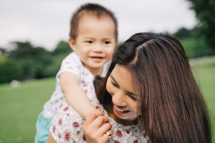 A kid playing with mother in a field