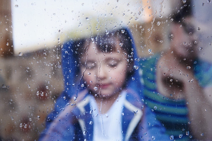 rainy weather little boy behind the glass 