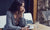 Woman sitting in a restaurant holding her mobile phone looking away