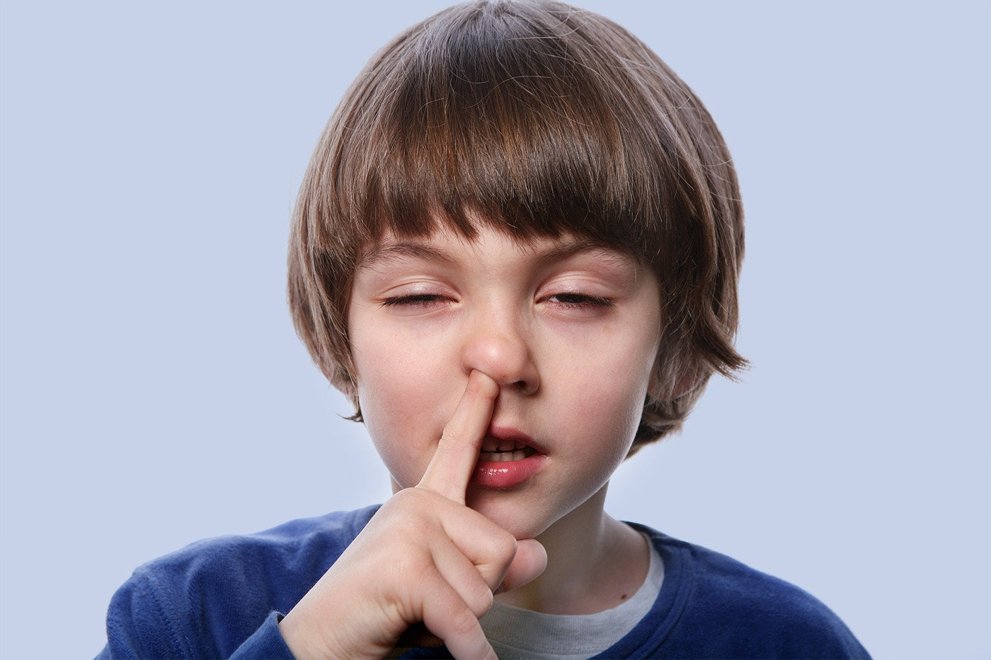 a young boy picking his nose