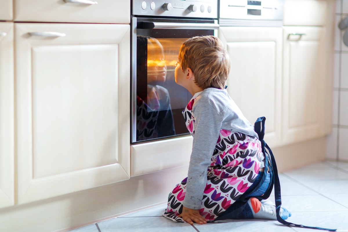 Young boy sitting in front of oven, looking through glass