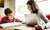 Mother helping son while he is studying and she is working on laptop at home 