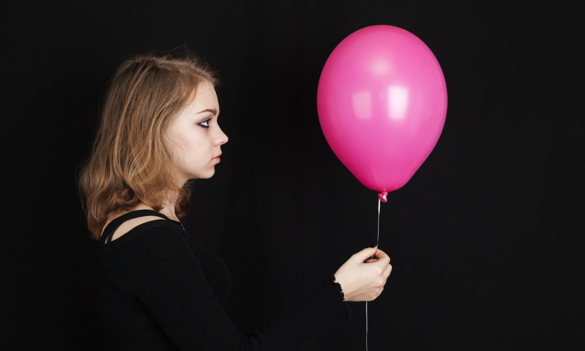 Young woman holding colorful pink balloon