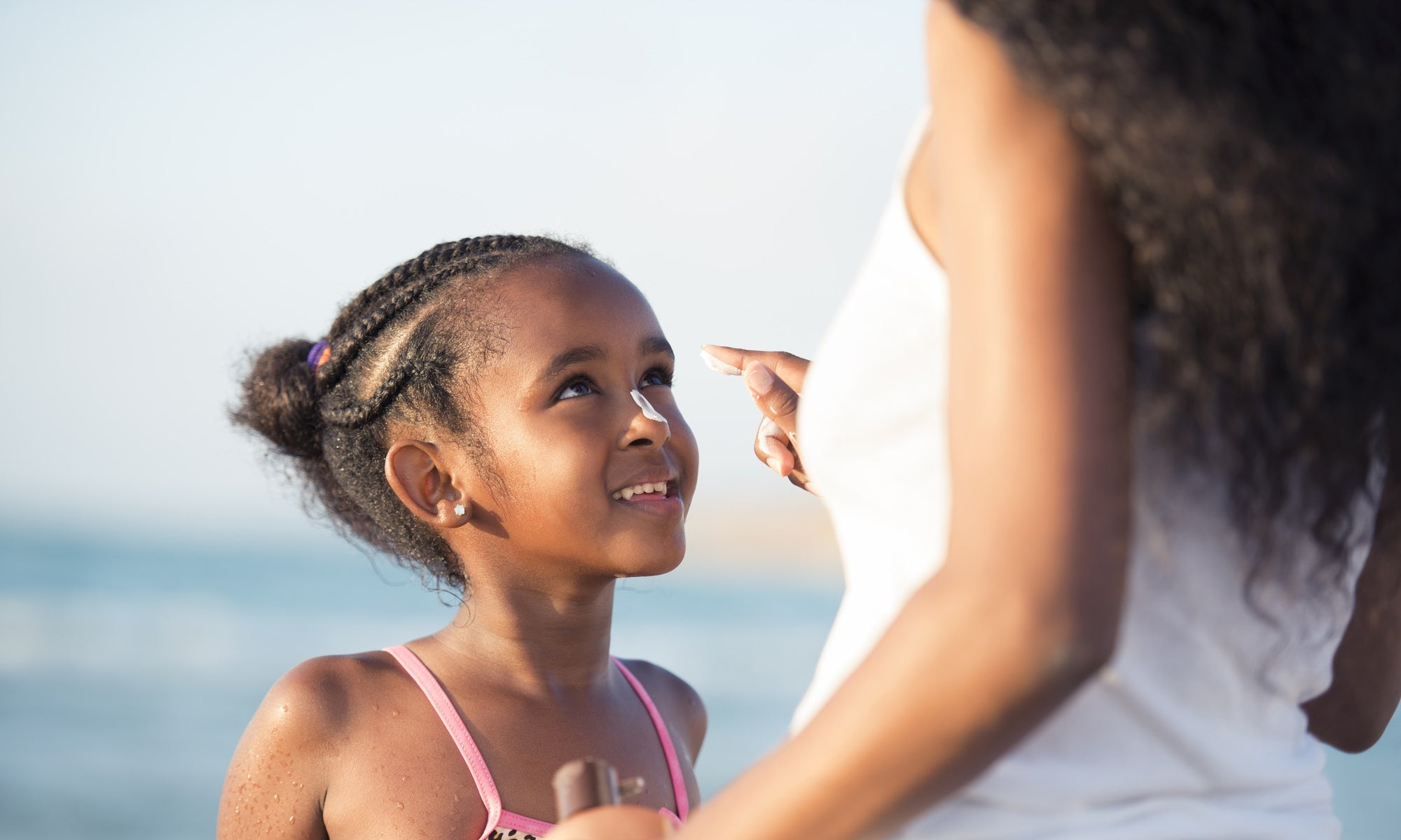 Mother applying moisturizer on daughters nose