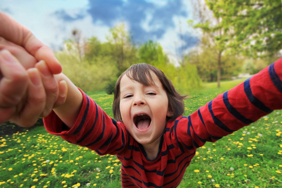 A boy is enjoying moment by hodling parents hand