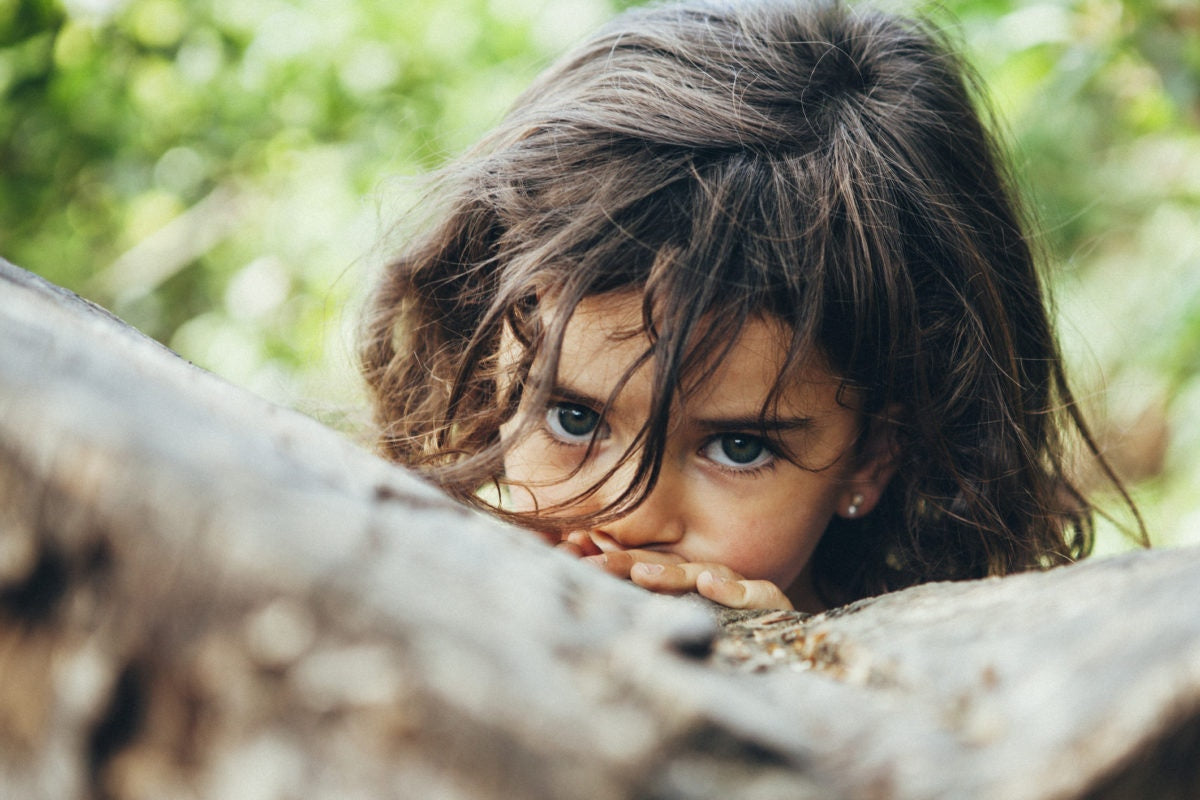 tensed girl peeking through rocks