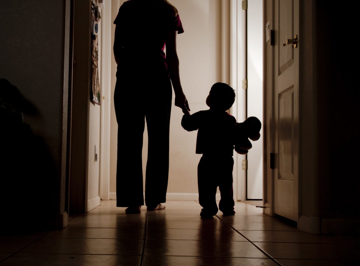 rear view of baby child holding mother hand walking on hallway