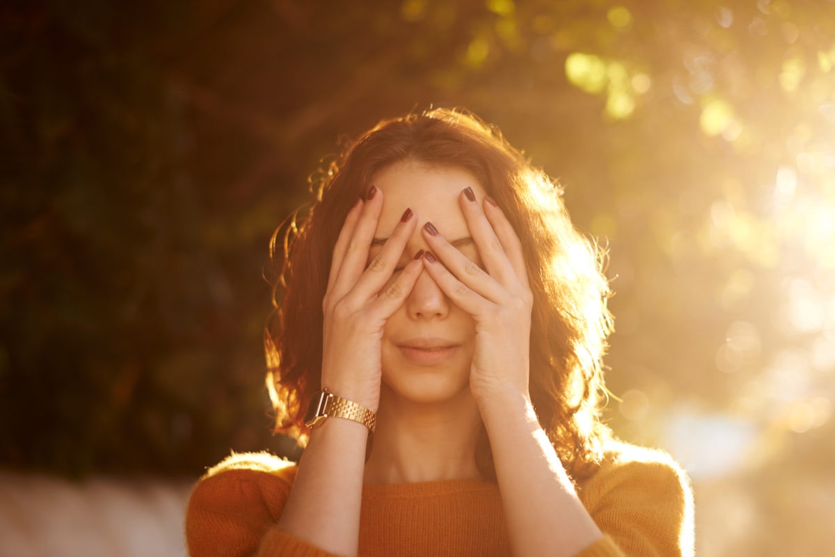 Young woman covering her eyes with her hands