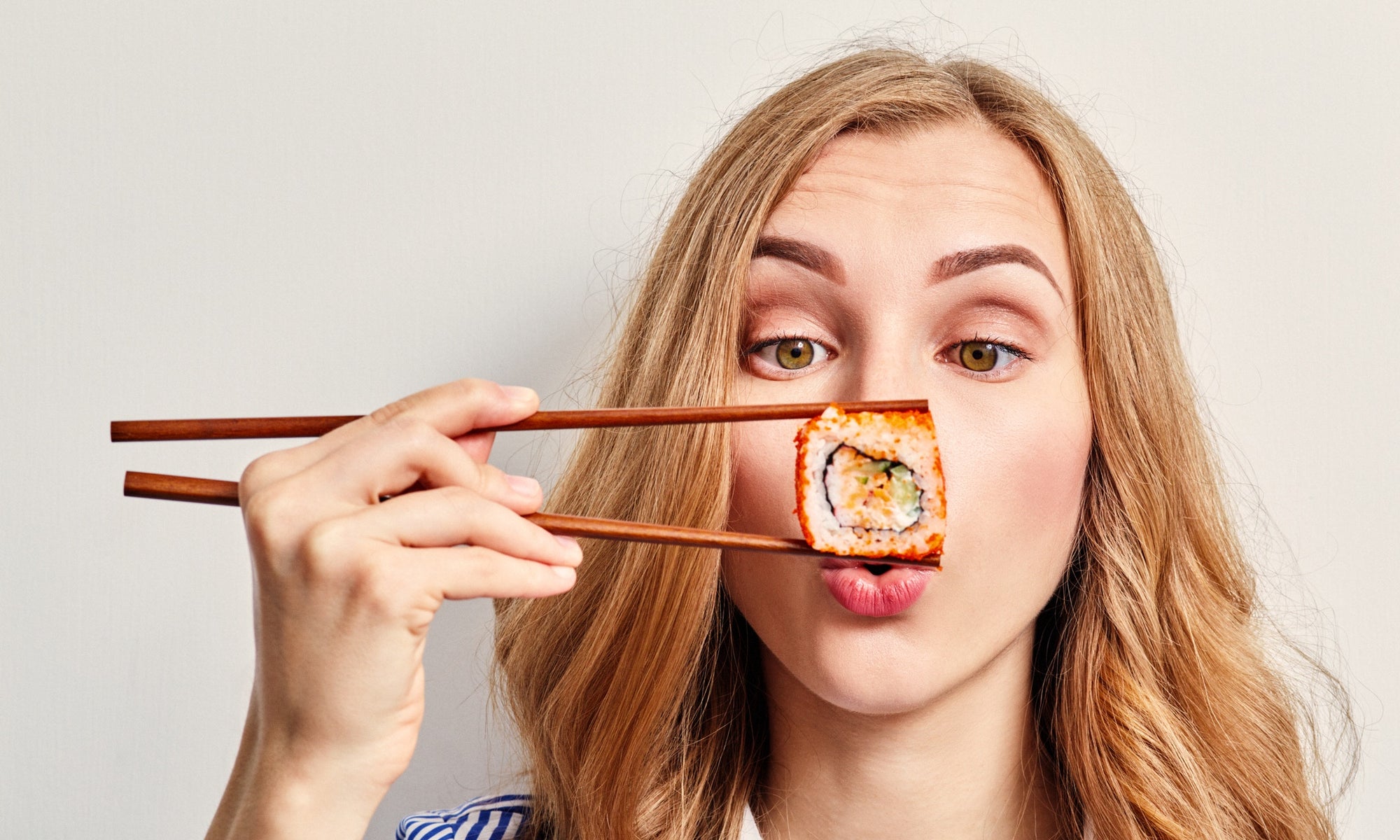 woman eating sushi with chopsticks