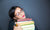 Woman resting her face on a pile of books.