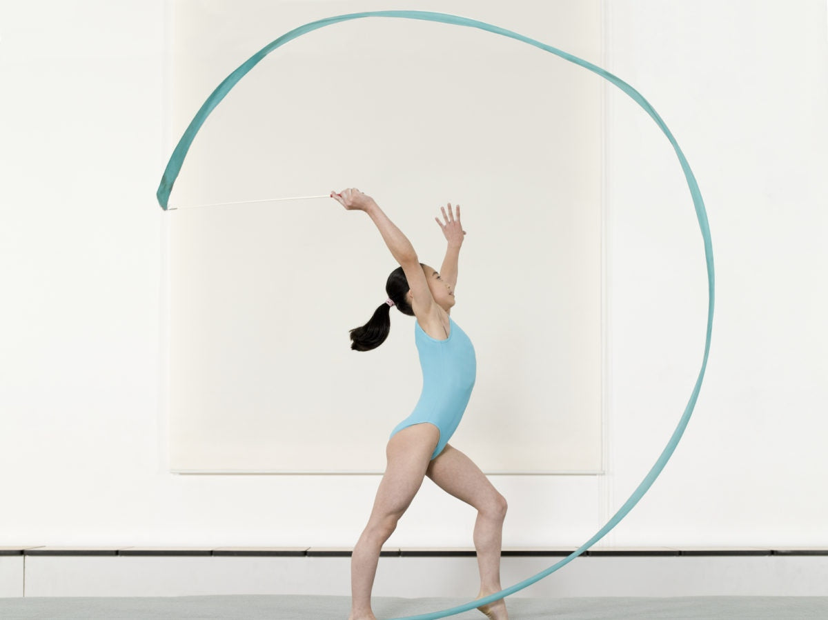 little girl playing with gymnastic ribbons in a clearing in nature