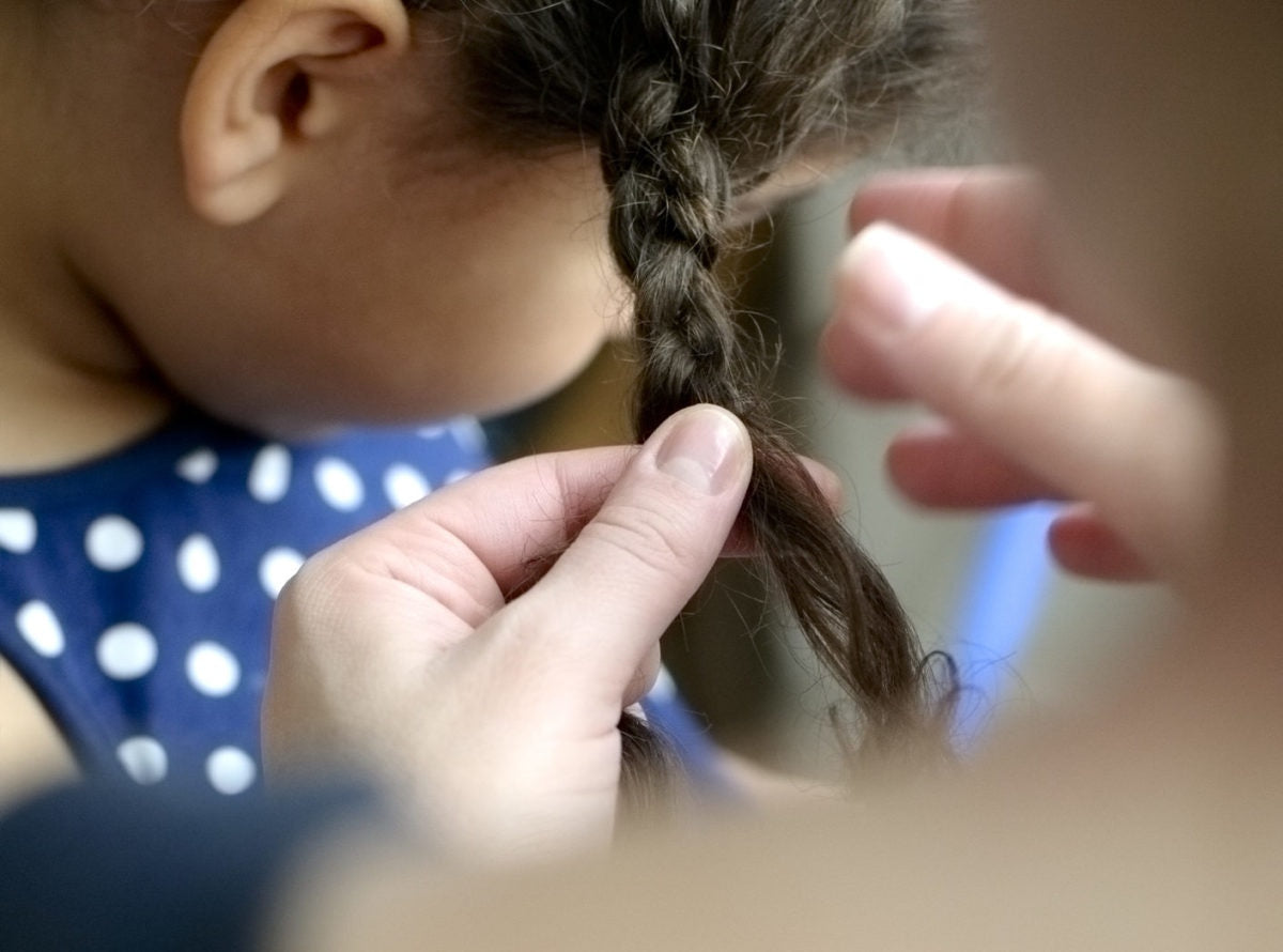 Mother is tieing daugher's hair