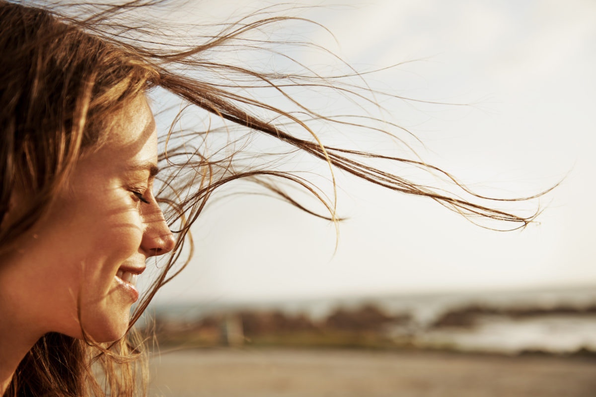 A woman is feeling happy by standing outside with closing her eyes