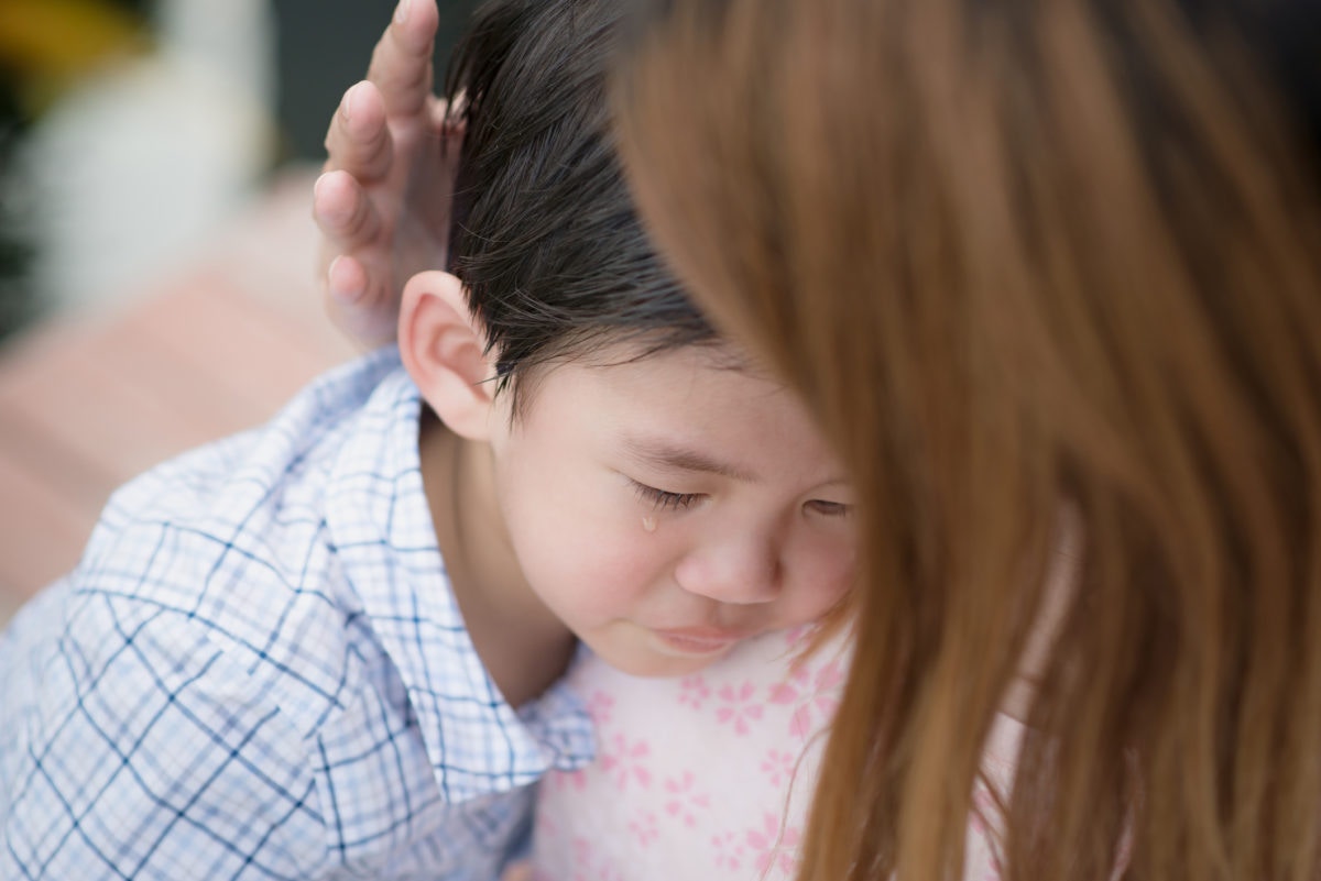 Lady is convincing a crying young boy