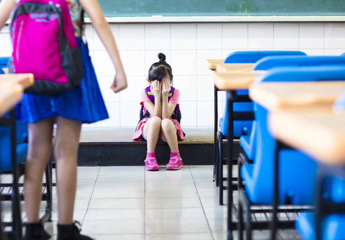 A girl is crying in a class room by closing her face