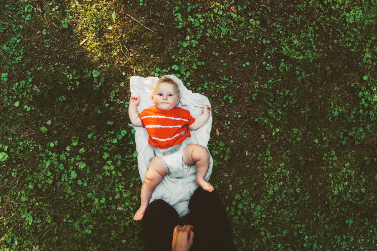 Overhead view of baby boy lying in garden on baby support seat