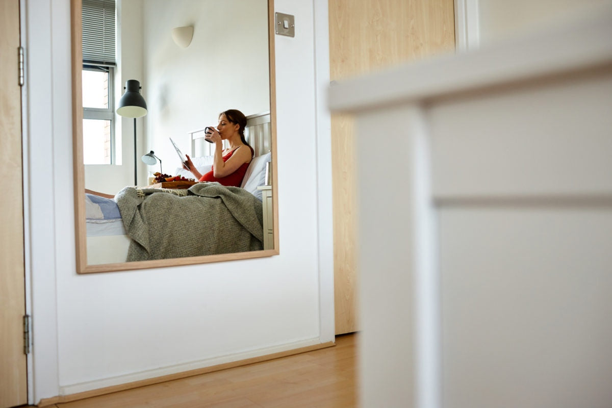 Pregnant woman eating fruits while sitting on bed