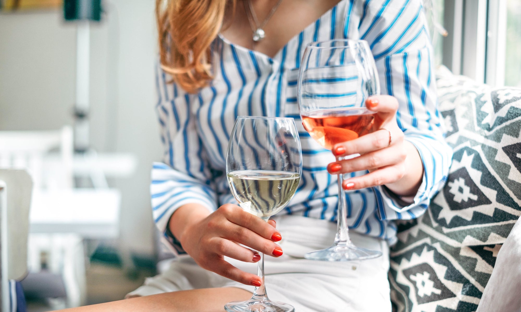 beautiful women sitting on couch holding glass of red and white wine