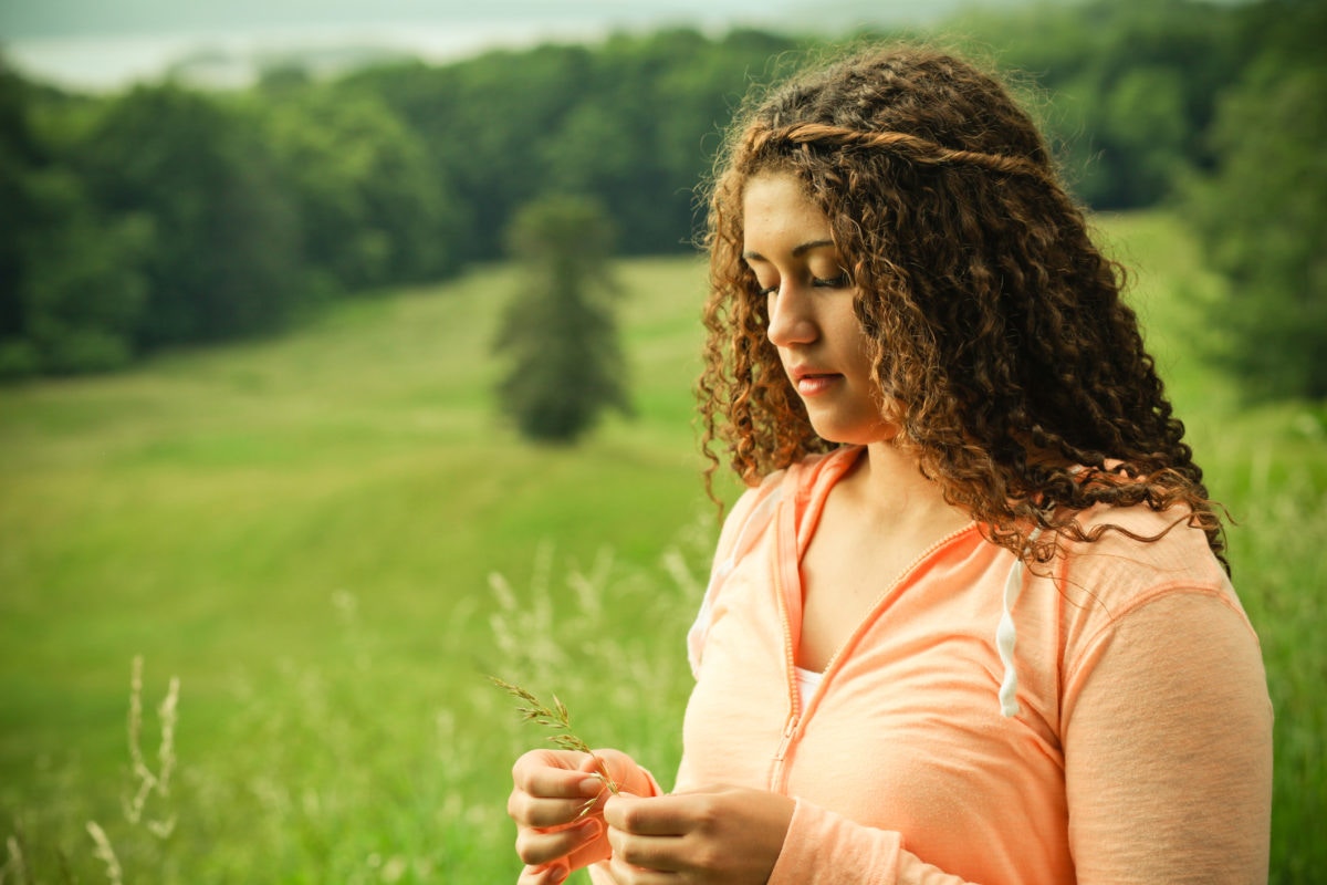 woman with curly hair in a orange hoodie against nature background