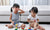 Two girls drawing with wax crayons, one girl crying