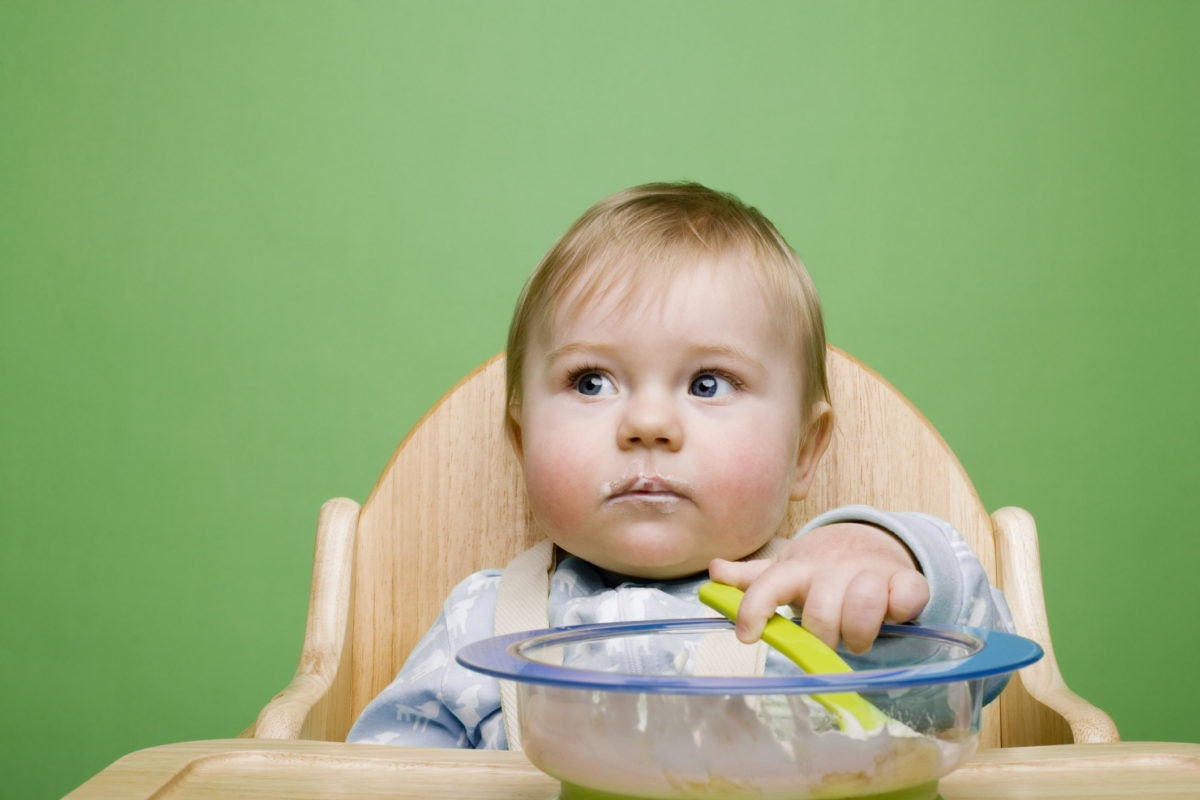 baby sitting in high chair eating carrot