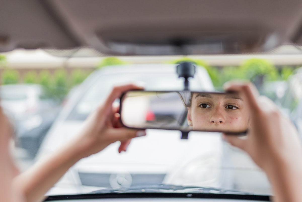 Young woman looking in rear view mirror