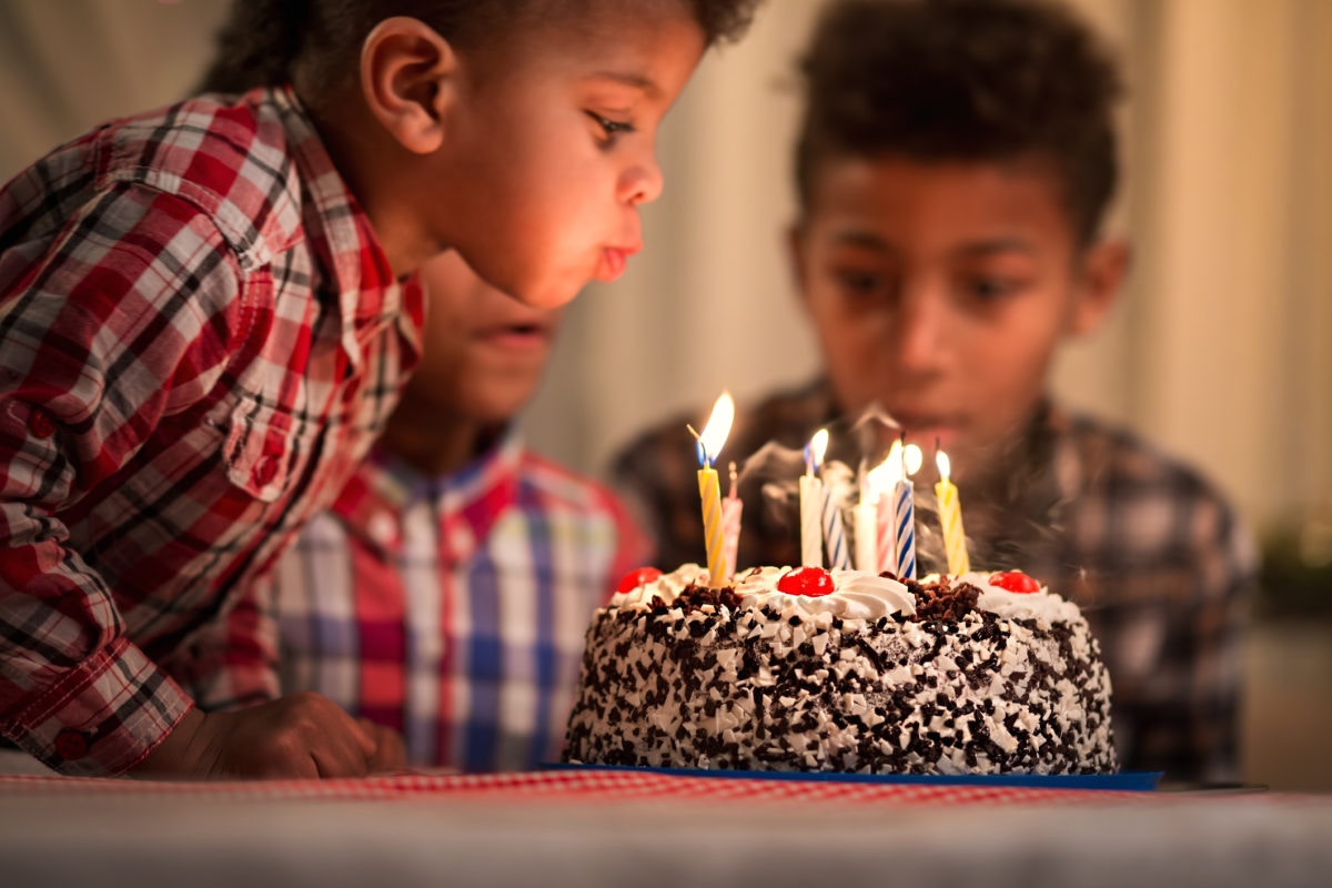 Young boy blowing out candles on birthday cake