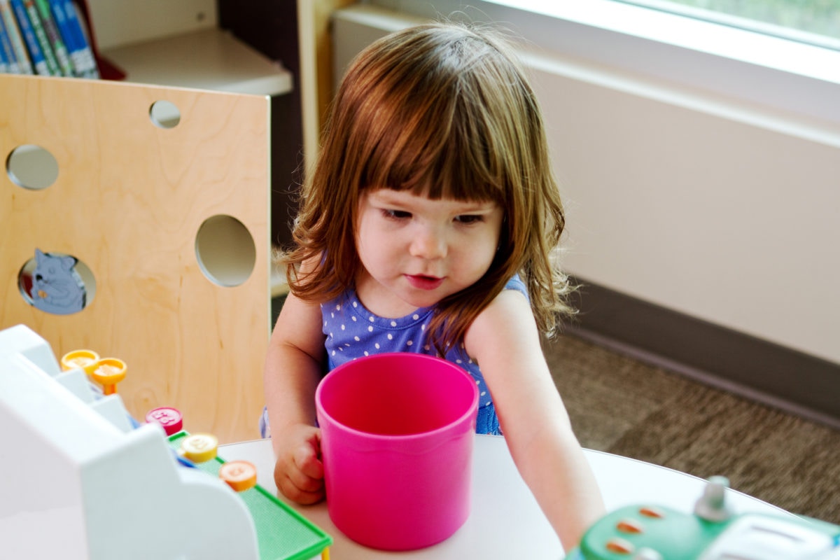 little girl with blonde hair playing with water and colors in kindergarden