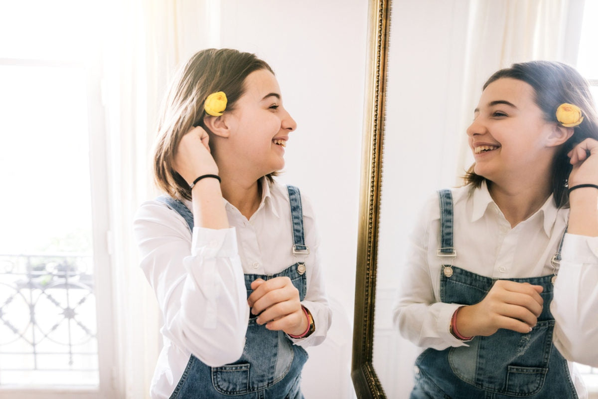 teenage girl looking at herself in the mirror and smiling
