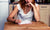 woman sitting at table writing in book