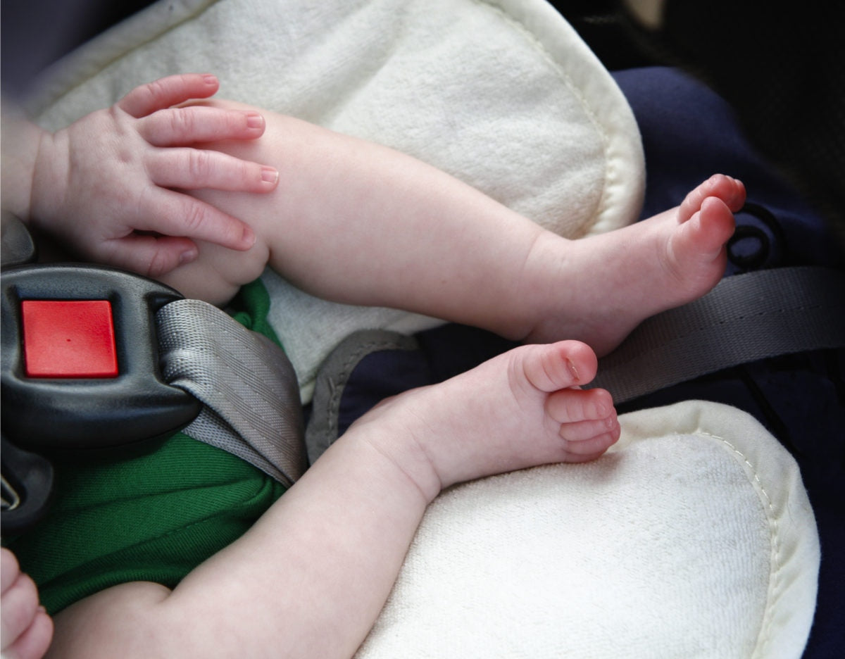 Little baby in child safety seat inside of car, closeup on legs