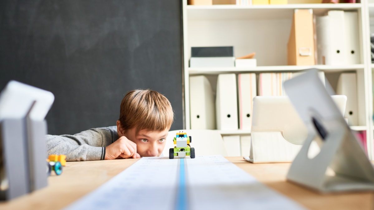 boy looking at his moving robotic toy car