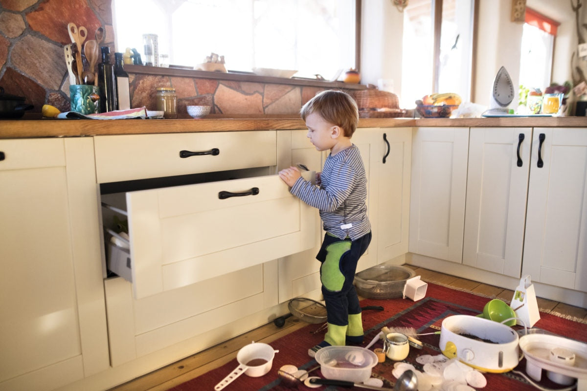 boy making a mess in the kitchen taking out all pots and pans