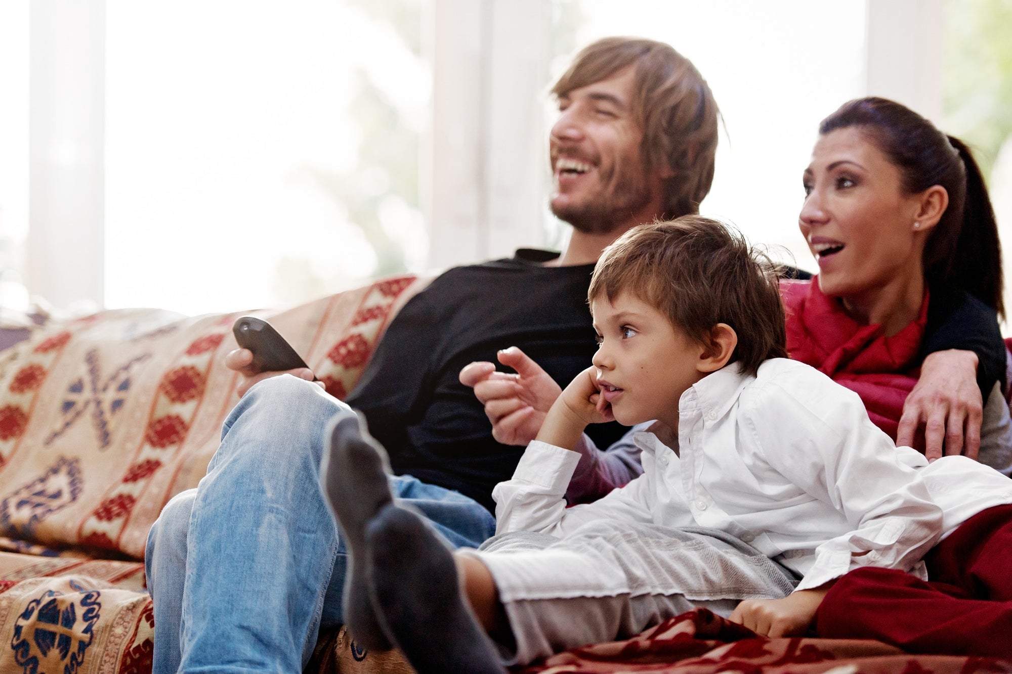 family on couch laughing while watching tv