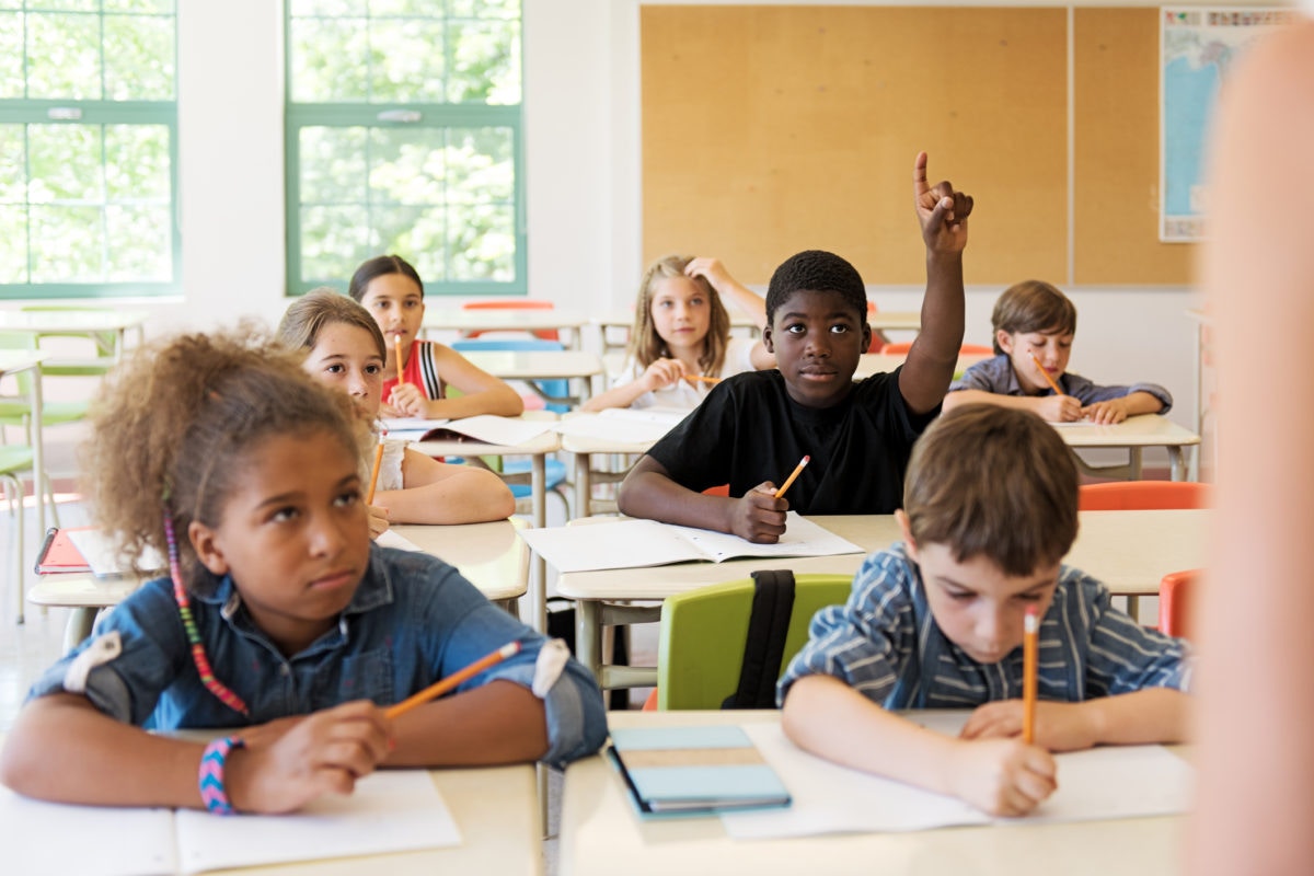 kids in school one holding hand in the air