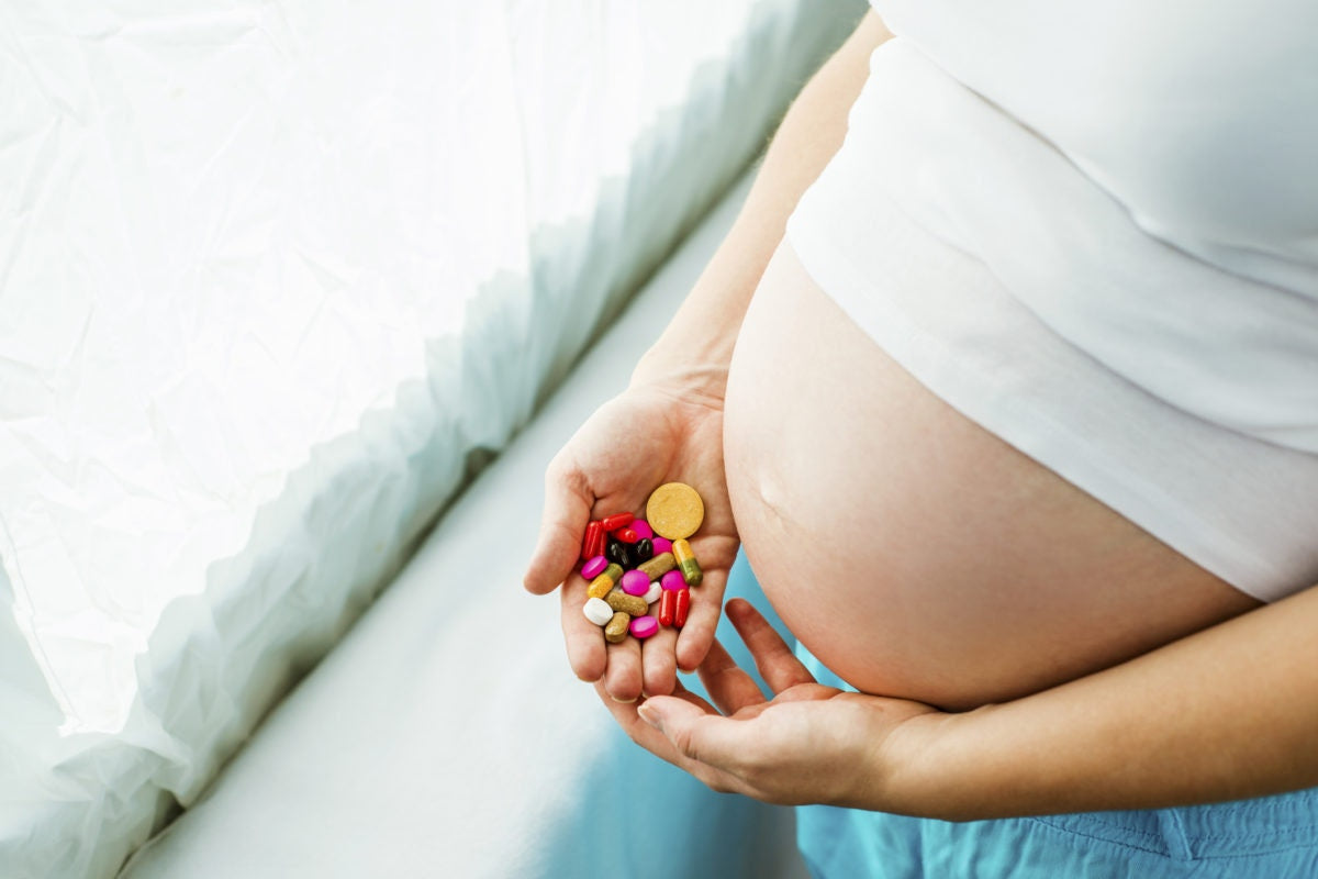 pregnant woman with medicine tablets in hand