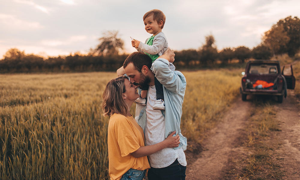 family time, boy on dad shoulders while kissing mom