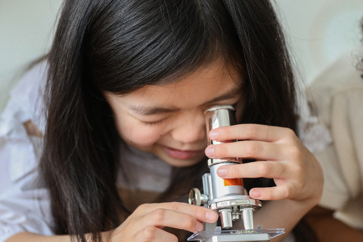 girl looking through a telescope