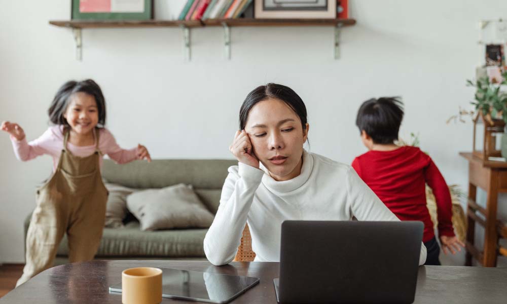 mom on computer while childern are playing