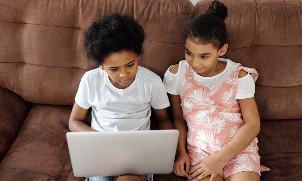 fratelli e sorelle seduti su un divano a guardare un computer