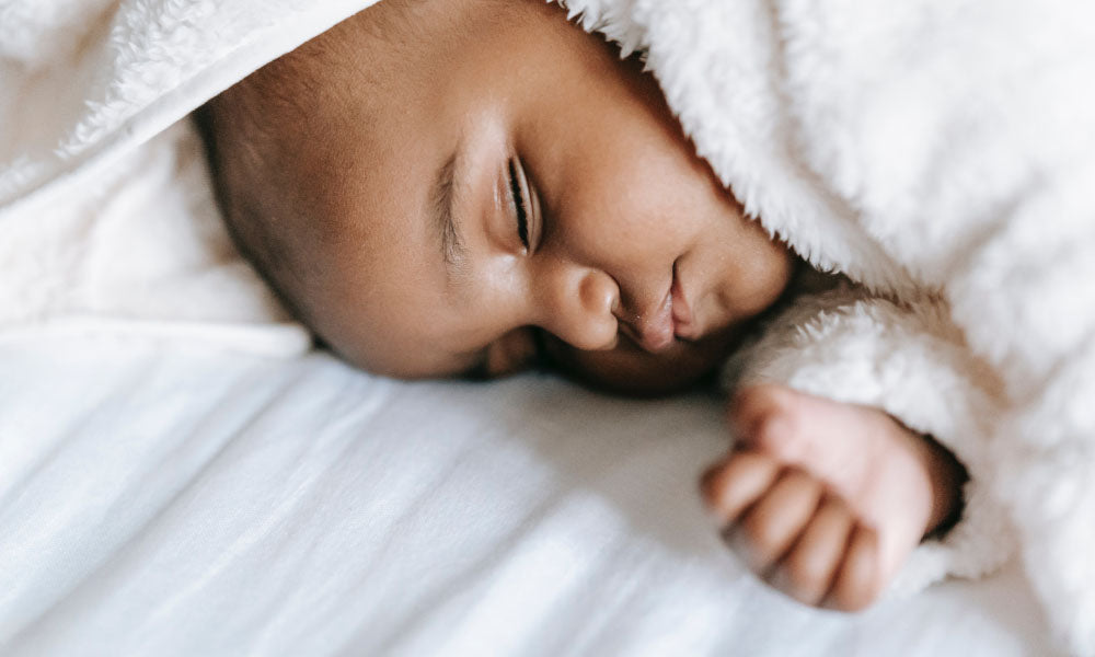 neonato che dorme sdraiato sulla schiena
