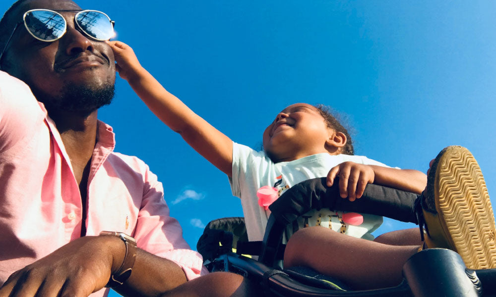 kid in stroller squeezing dad's cheeks