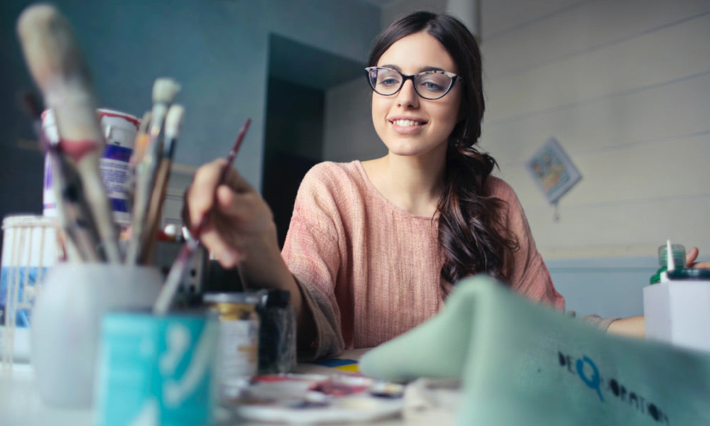 woman with paintbrushes doing art project 